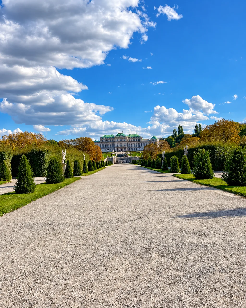 Kiesweg im Belvederegarten mit Hecken und Statuen, im Hintergrund das Obere Belvedere